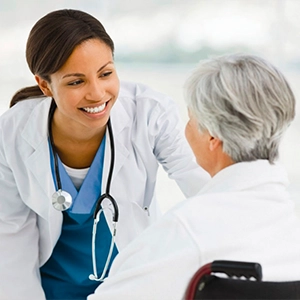 Smiling female doctor talking to a senior patient in a wheelchair.