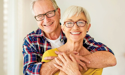 Smiling senior couple embracing and looking at the camera